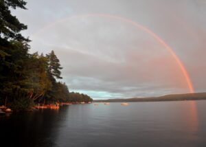 Color photograph of a double rainbow over a lake.
